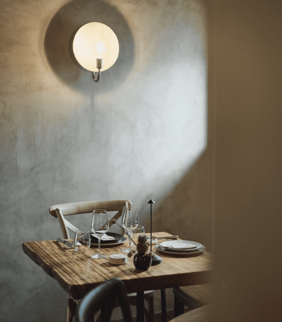 Parede de cal com candeeiro e mesa de madeira no Pão & Pizza